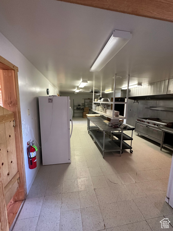 Basement featuring white refrigerator and tile flooring