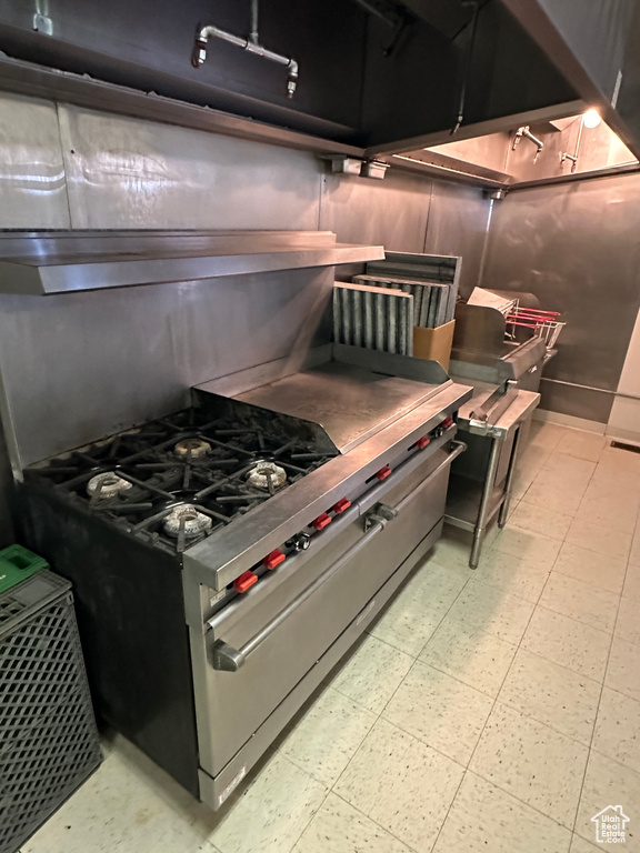 Kitchen with high end stainless steel range, stainless steel counters, and light tile floors