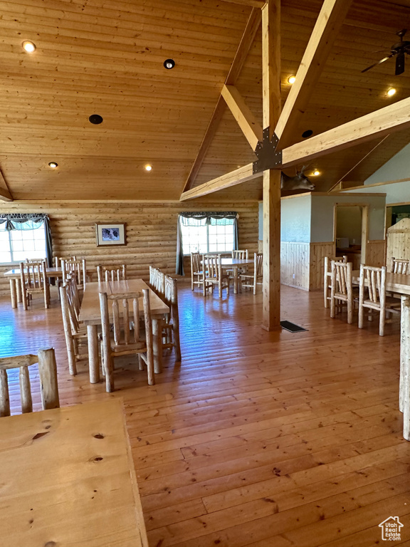 Dining room with wooden ceiling, a healthy amount of sunlight, rustic walls, and wood-type flooring