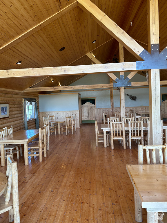 Unfurnished dining area with wooden ceiling, lofted ceiling with beams, log walls, and wood-type flooring