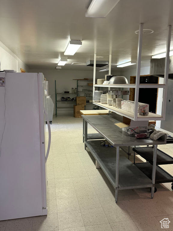 Kitchen with light tile flooring and white refrigerator