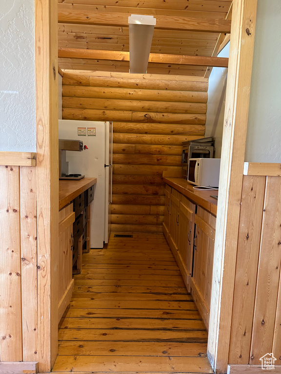 Kitchen featuring beam ceiling, log walls, and light hardwood / wood-style flooring