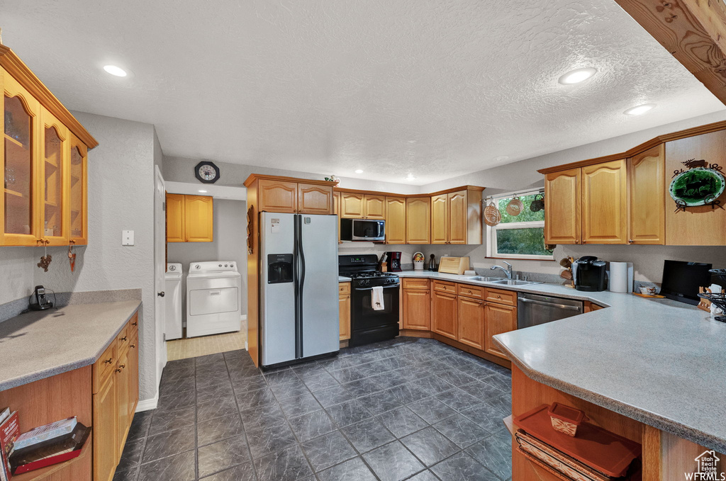 Kitchen with washing machine and dryer, dark tile flooring, stainless steel appliances, and sink