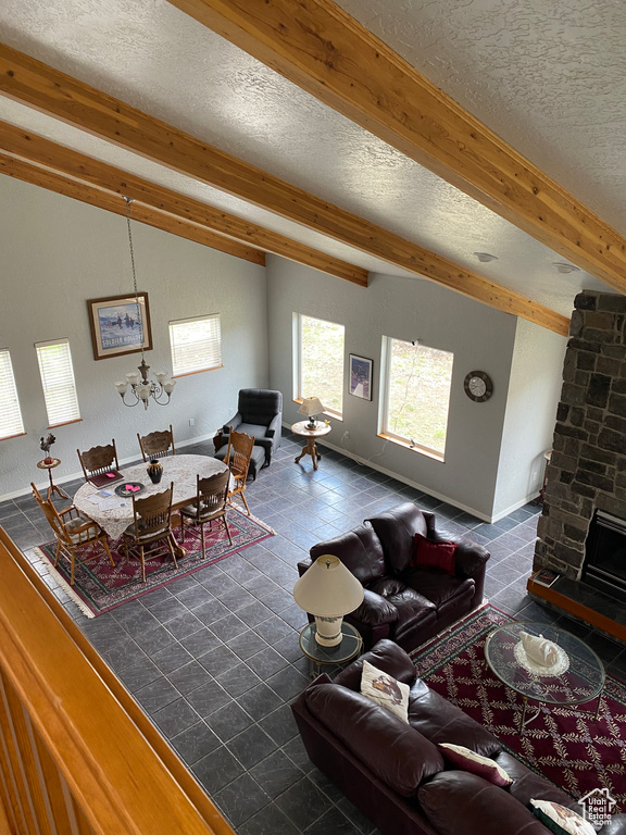 Tiled living room with brick wall, a fireplace, a textured ceiling, and beam ceiling