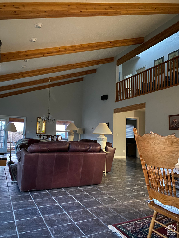 Living room featuring an inviting chandelier, high vaulted ceiling, beamed ceiling, and dark tile patterned floors