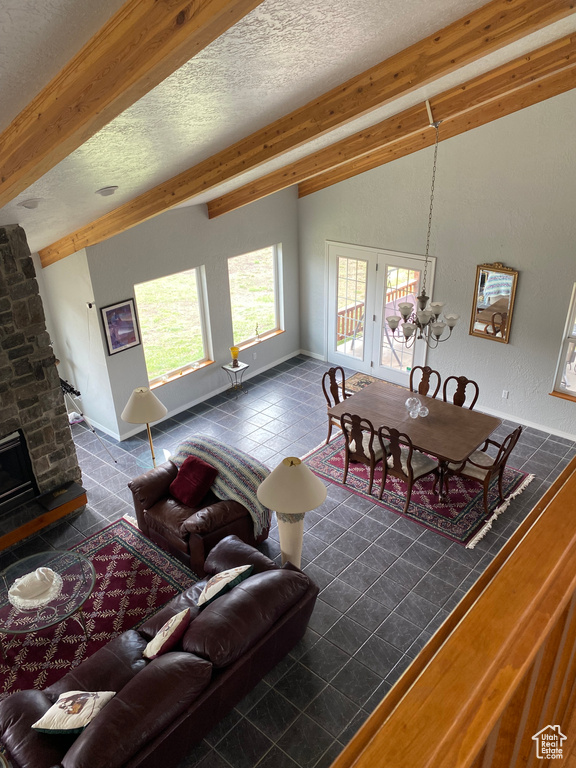 Living room with french doors, a textured ceiling, brick wall, dark tile patterned flooring, and a stone fireplace