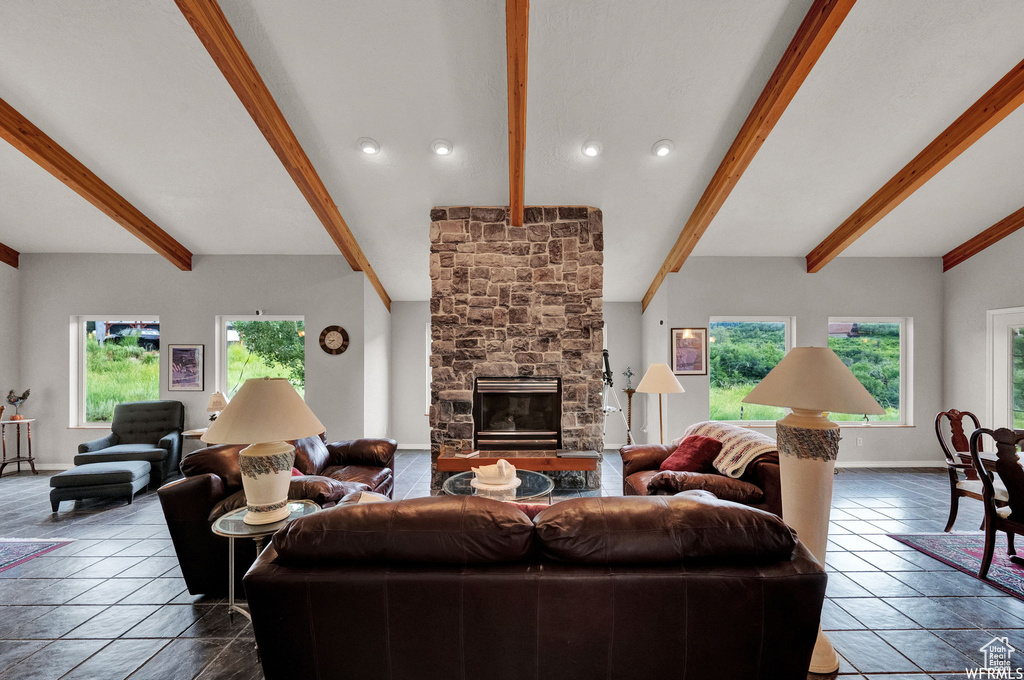 Tiled living room with a stone fireplace and lofted ceiling with beams