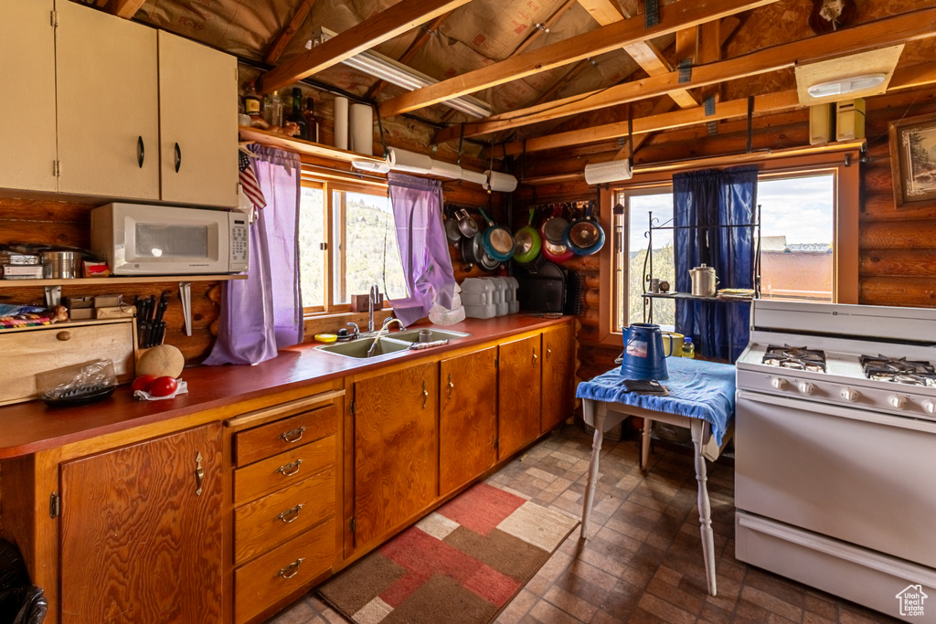 Kitchen featuring sink, lofted ceiling with beams, white appliances, and rustic walls