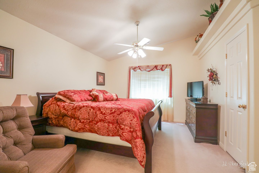 Carpeted bedroom with ceiling fan and lofted ceiling