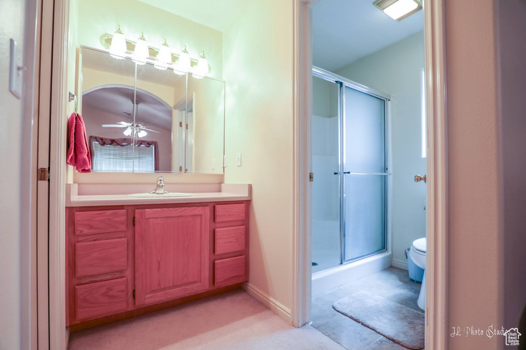 Bathroom featuring ceiling fan, an enclosed shower, vanity, and toilet