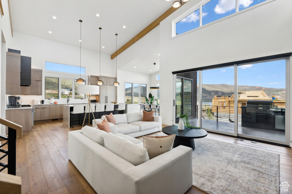 Living room with a healthy amount of sunlight, beamed ceiling, hardwood / wood-style floors, and a towering ceiling