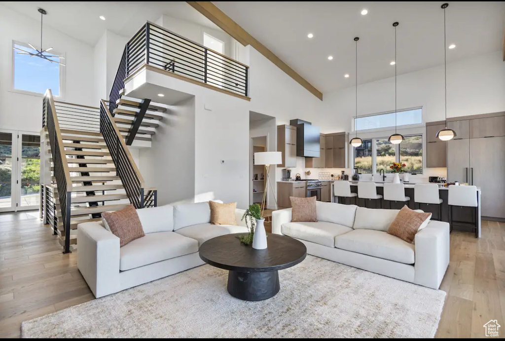 Living room with a high ceiling, an inviting chandelier, and light hardwood / wood-style flooring