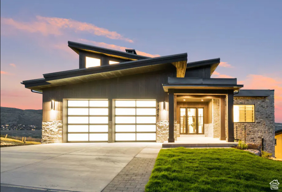 View of front facade featuring a garage and a yard