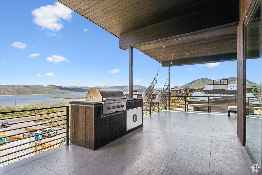 View of patio featuring a balcony, a water view, and grilling area