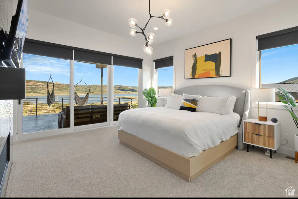 Carpeted bedroom with an inviting chandelier, a water view, and access to exterior