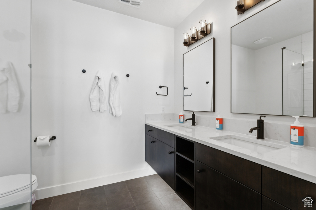 Bathroom with tile flooring, toilet, and dual bowl vanity