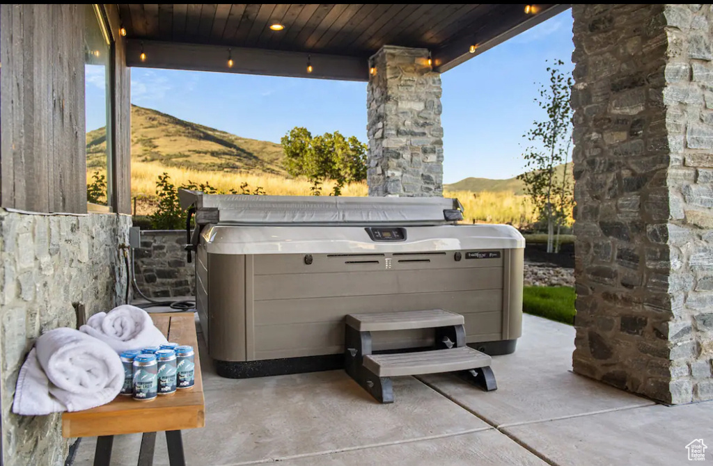 View of patio with a mountain view and a hot tub