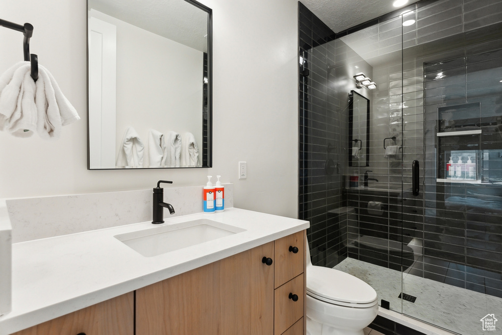 Bathroom featuring a shower with shower door, oversized vanity, and toilet