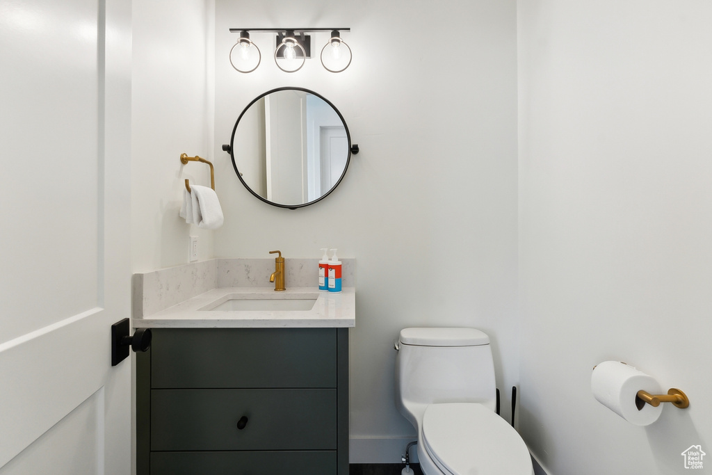 Bathroom featuring vanity with extensive cabinet space and toilet