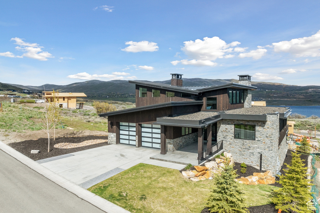 View of front of property featuring a garage and a water and mountain view