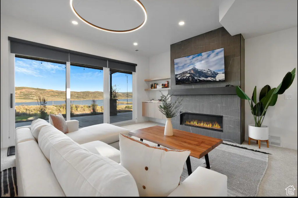 Living room featuring light carpet, a water view, plenty of natural light, and a fireplace