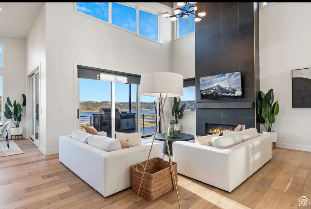 Living room with a towering ceiling, a water view, light hardwood / wood-style floors, and a tile fireplace