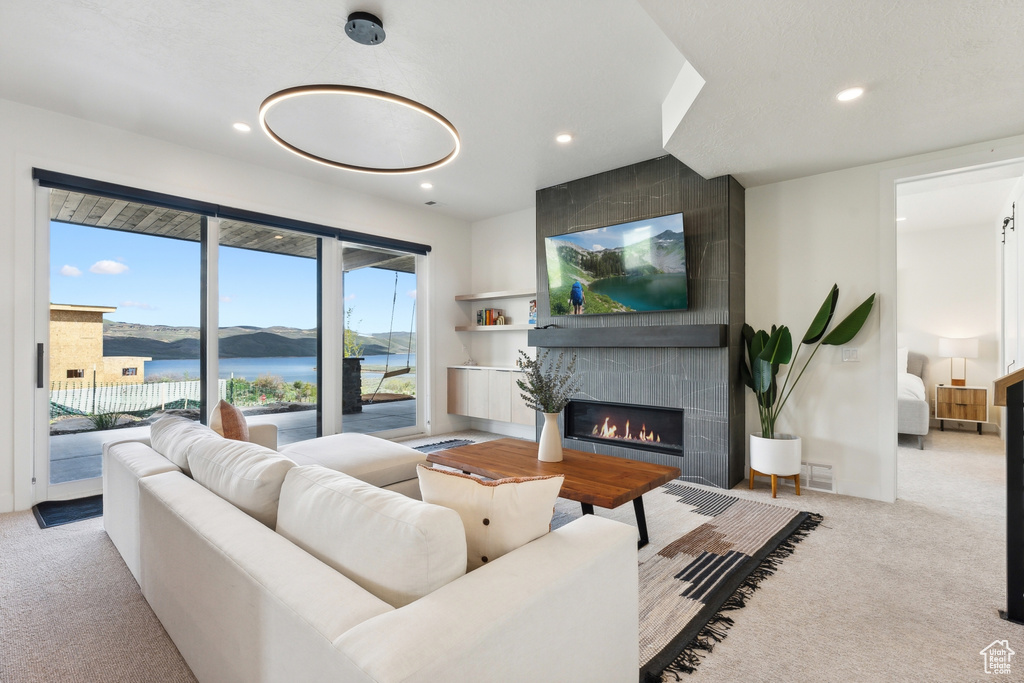 Carpeted living room featuring a tiled fireplace and a water view