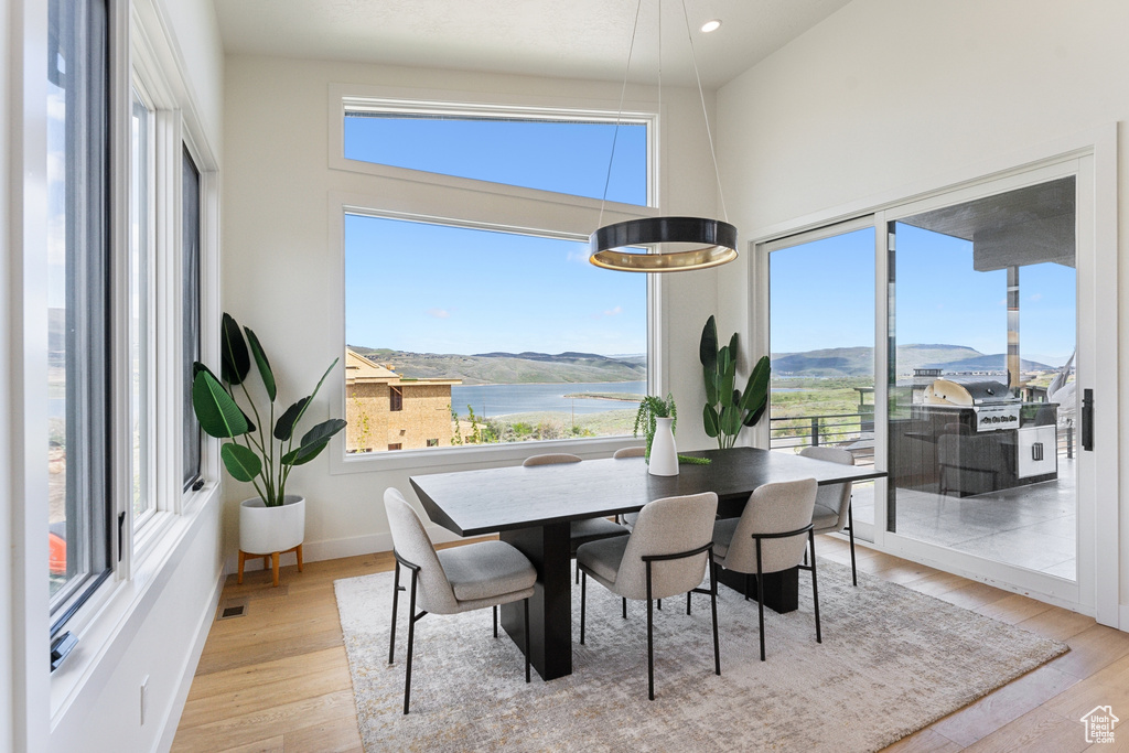 Dining room with high vaulted ceiling, a water and mountain view, plenty of natural light, and light wood-type flooring