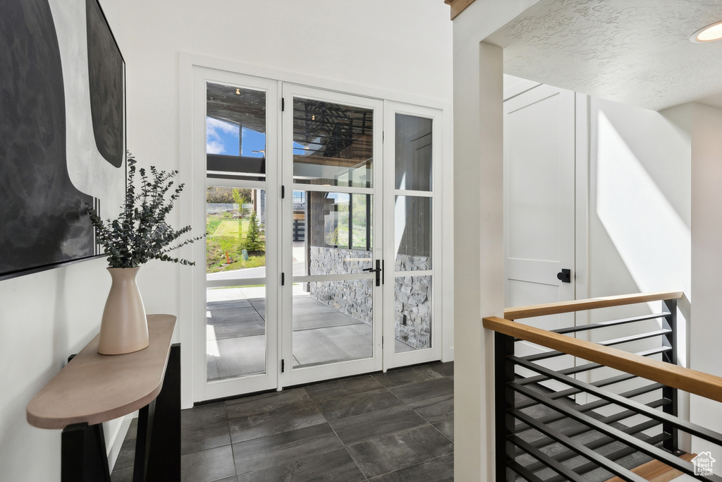 Doorway to outside with dark tile floors and french doors