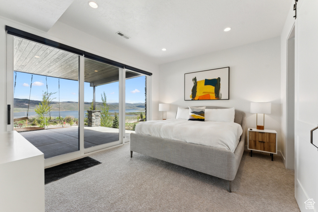 Carpeted bedroom featuring a water view and access to exterior