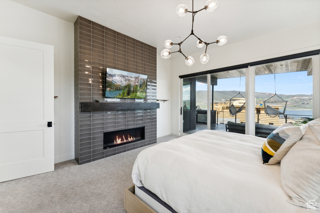 Bedroom featuring a water view, a chandelier, carpet floors, and a fireplace