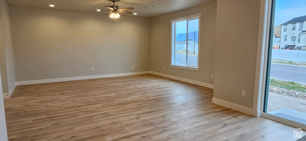 Unfurnished room featuring a healthy amount of sunlight, light hardwood / wood-style floors, and ceiling fan