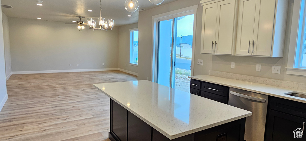 Kitchen featuring light wood-type flooring, dishwasher, a center island, white cabinetry, and hanging light fixtures