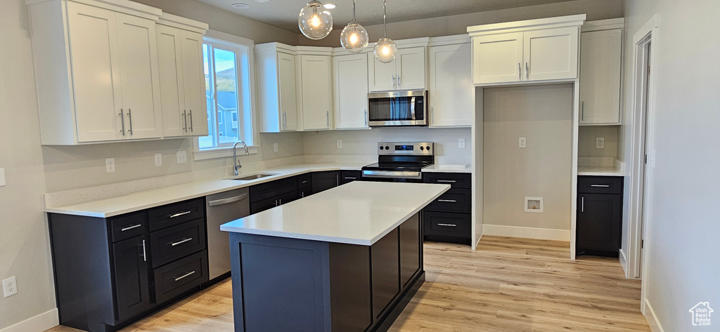 Kitchen featuring pendant lighting, a center island, sink, white cabinetry, and appliances with stainless steel finishes