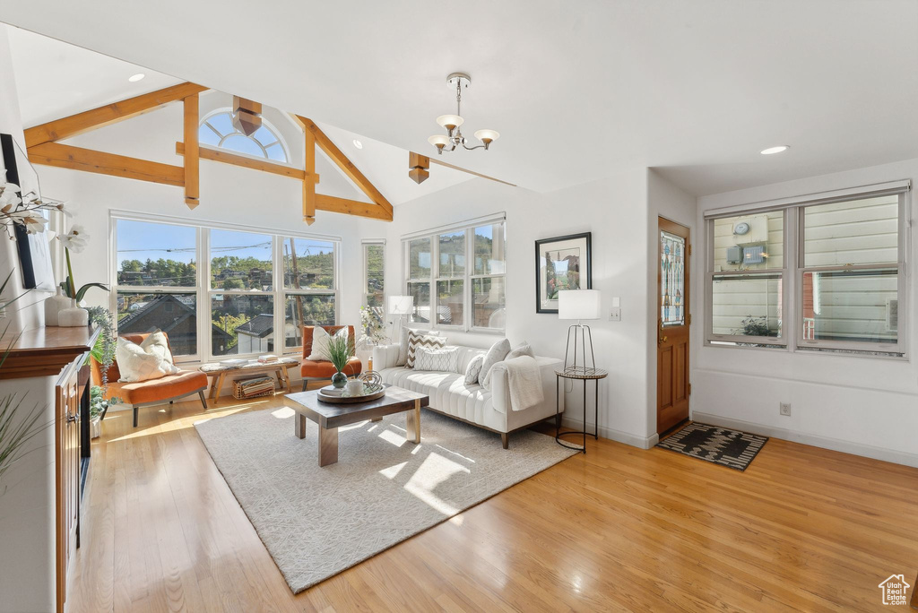 Living room featuring lofted ceiling, light hardwood / wood-style floors, and a notable chandelier