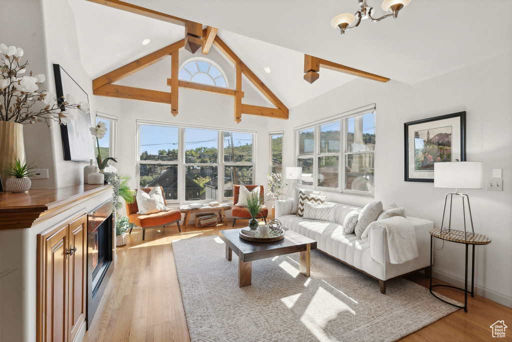 Living room with lofted ceiling with beams, a chandelier, and light hardwood / wood-style floors