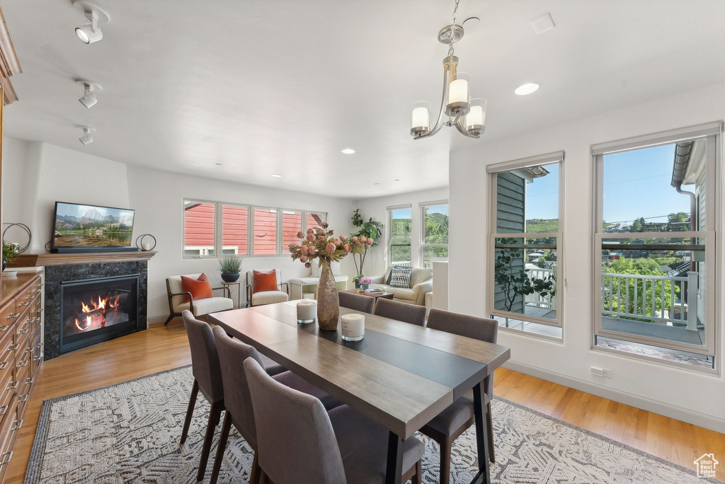 Dining room with a high end fireplace, light hardwood / wood-style flooring, and a chandelier