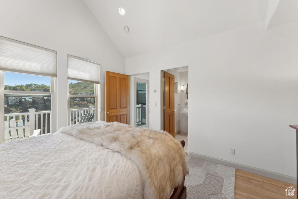 Bedroom with access to exterior, high vaulted ceiling, ensuite bathroom, and light hardwood / wood-style floors