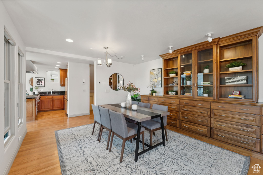 Dining area with sink, light wood-type flooring, and a notable chandelier