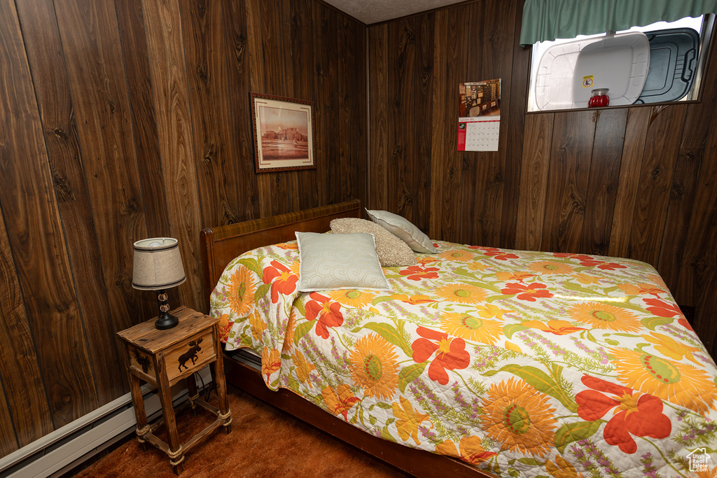 Bedroom featuring a baseboard heating unit and wood walls