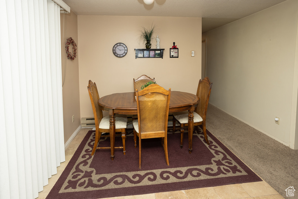 Carpeted dining space featuring baseboard heating