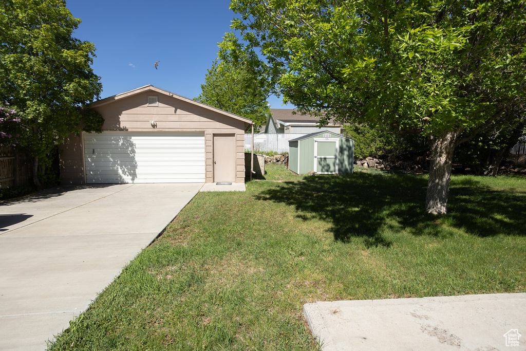 View of front facade with a garage, a front yard, and a storage shed