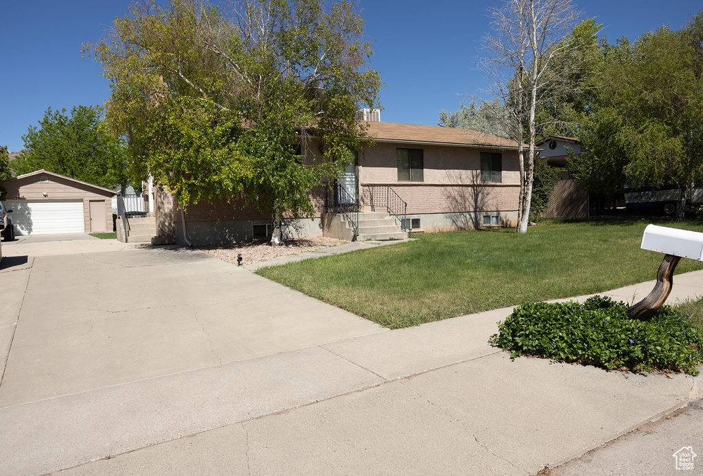 View of front of home featuring a front yard, a garage, and an outdoor structure