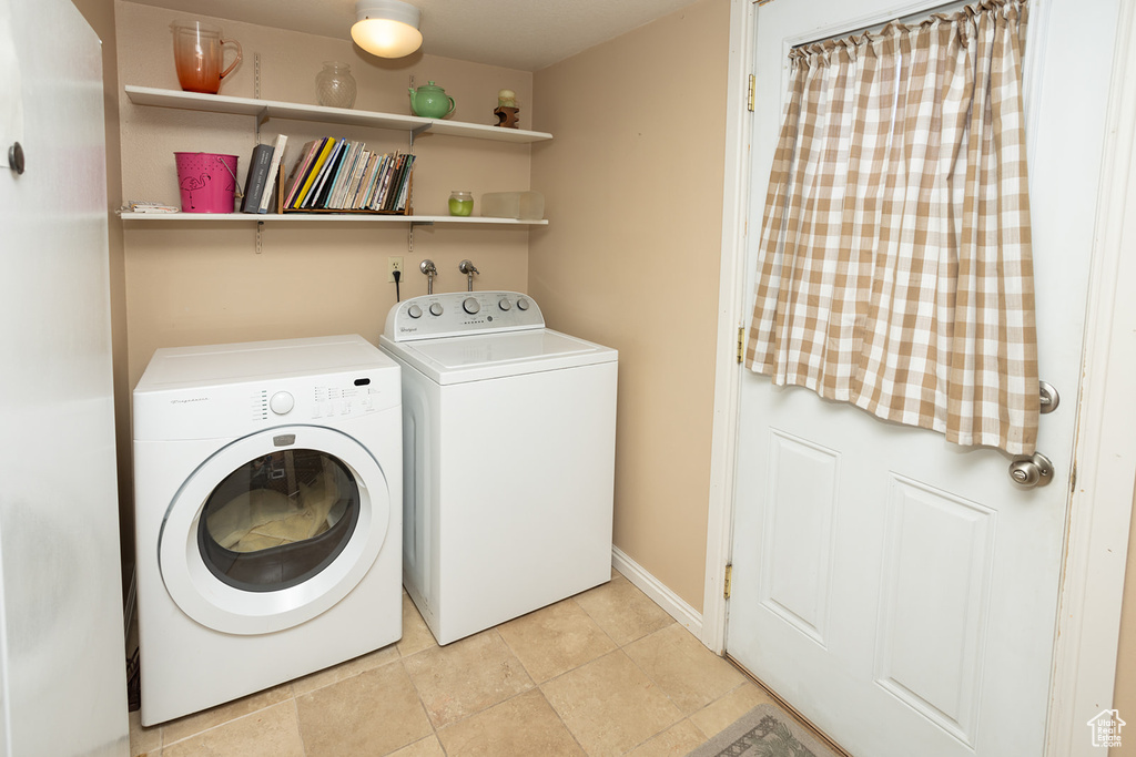 Washroom with washer hookup, independent washer and dryer, and light tile floors