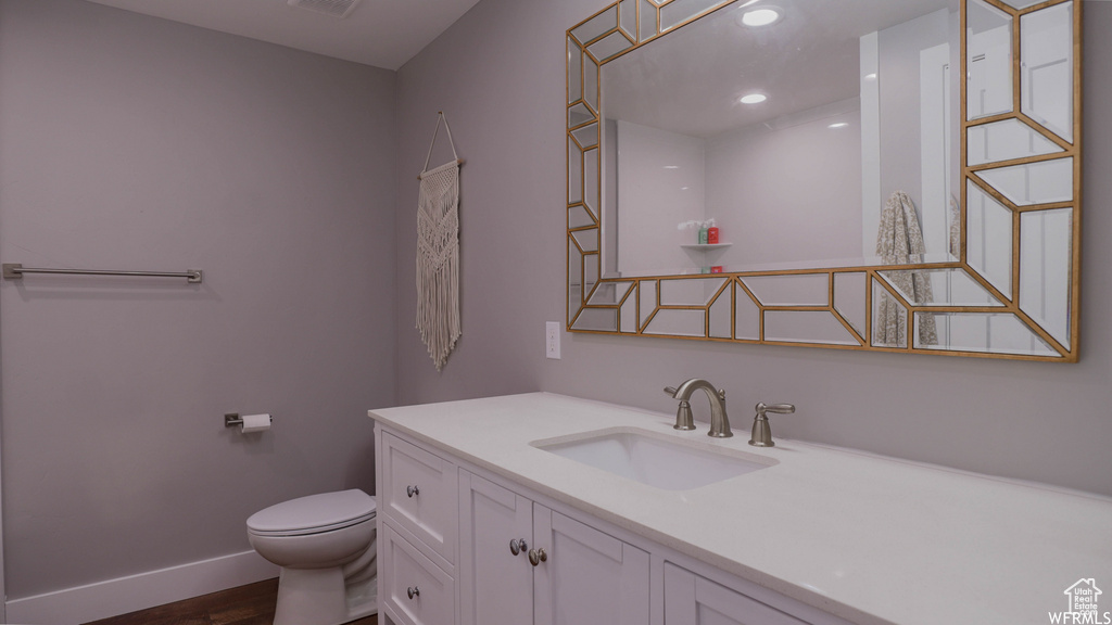 Bathroom featuring hardwood / wood-style floors, vanity, and toilet