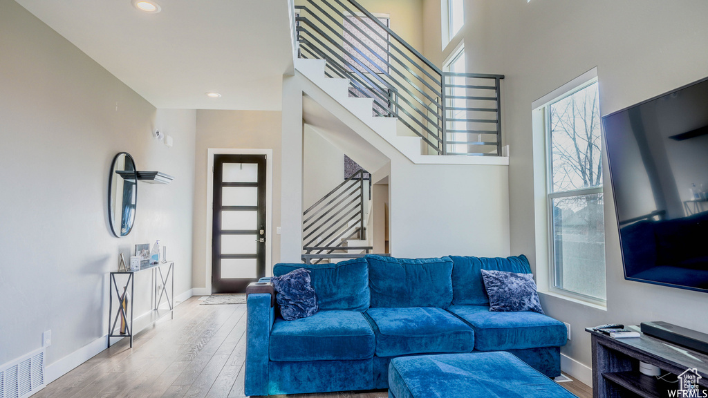 Living room featuring plenty of natural light, a towering ceiling, and hardwood / wood-style floors