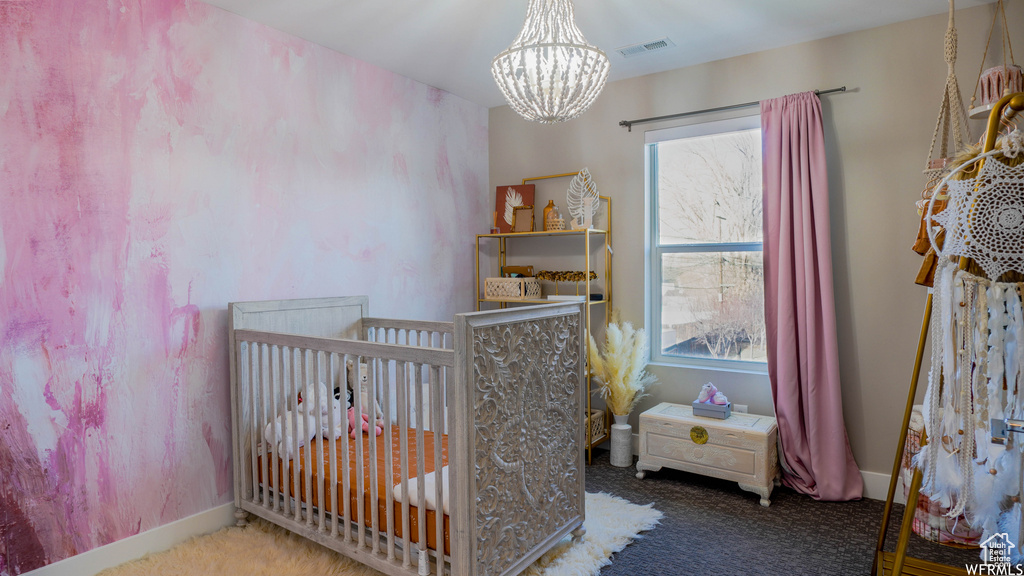 Bedroom featuring a crib, a chandelier, and multiple windows