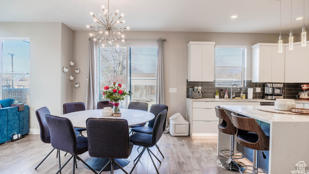 Dining area featuring sink, light hardwood / wood-style floors, a wealth of natural light, and a chandelier