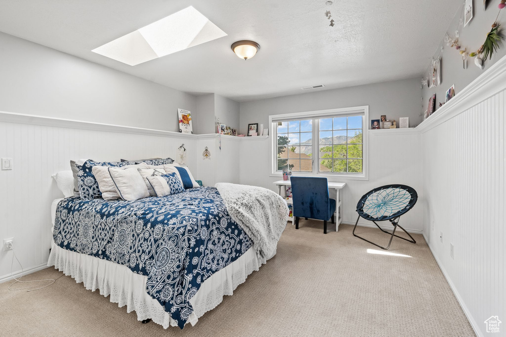 Bedroom with a skylight and light colored carpet