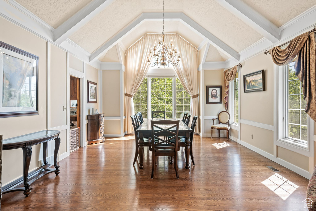 Dining space with a notable chandelier, vaulted ceiling, hardwood / wood-style floors, and a textured ceiling